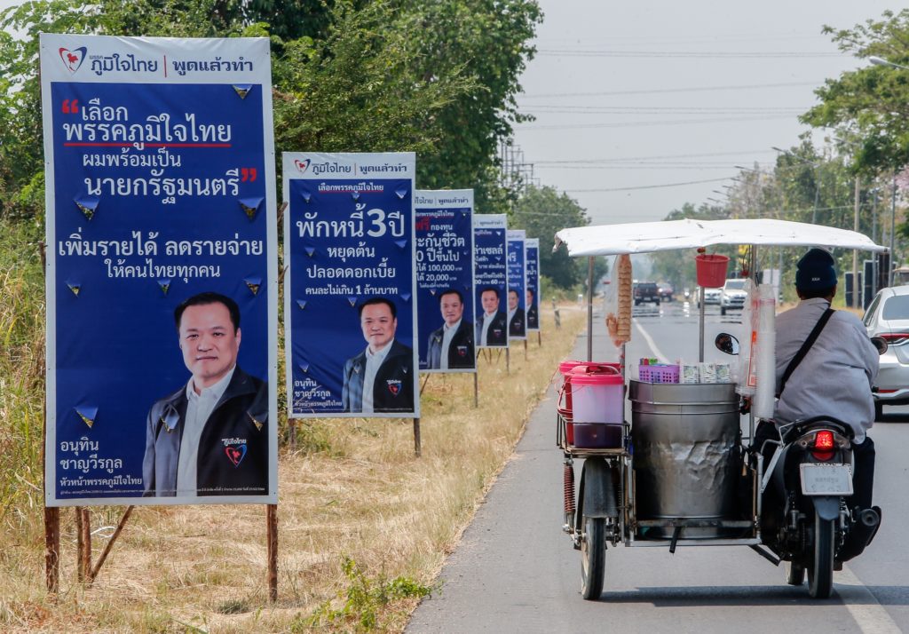 Мотоцикл с коляской проезжает мимо агитационных плакатов Анутина Чарнвиракула в провинции Накхонсаван, к северу от Бангкока (Фото: Чайват Субпрасом / Getty Images)