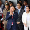 Бывший премьер-министр Таксин Чинават улыбается и приветствует сторонников жестом «вай» выходя из терминала частных самолетов в аэропорту Донмыанг (Фото: Вичан Чароенкиатпакул)
